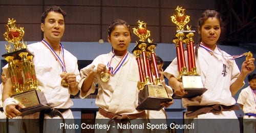 A young female athlete holding trophies and medals.