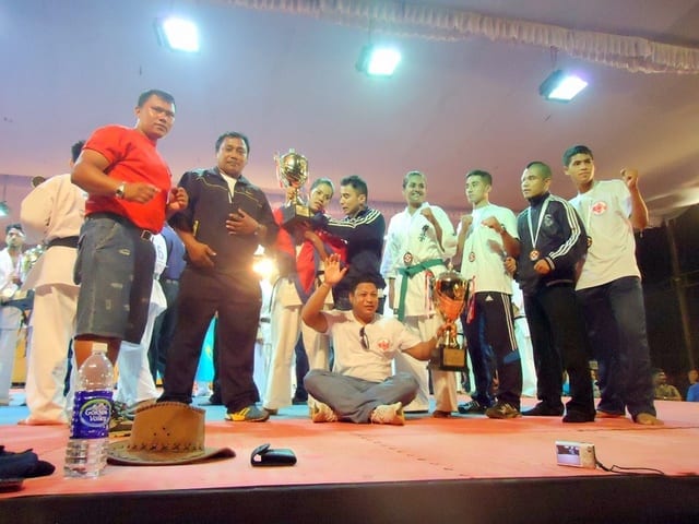 An athlete holding a large trophy, draped in the Nepali flag, at the 13th Asian Open.