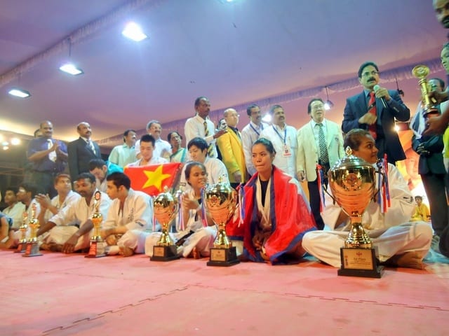 An athlete holding a large trophy, draped in the Nepali flag, at the 13th Asian Open.