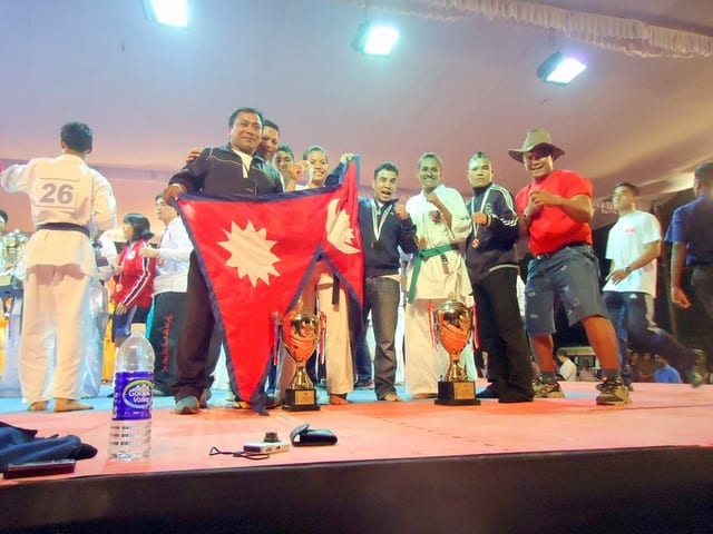 A stage ceremony with the Nepali flag and a medal podium.
