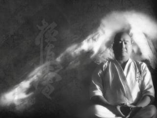 Masutatsu Oyama seated in seiza in mist, with a kanji overlay.