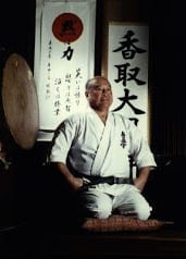 Masutatsu Oyama seated before a taiko drum, beneath a kanji banner.